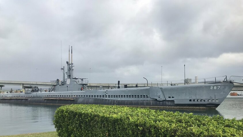 Ein historisches U-Boot im Hafen von Pearl Harbor, Hawaii, unter einem wolkigen Himmel.