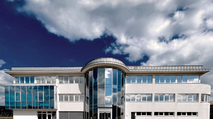 Außenaufnahme des Verwaltungstraktes der Entwicklungszentrale von weba in Dietach unter einem blauen Himmel mit Wolken.